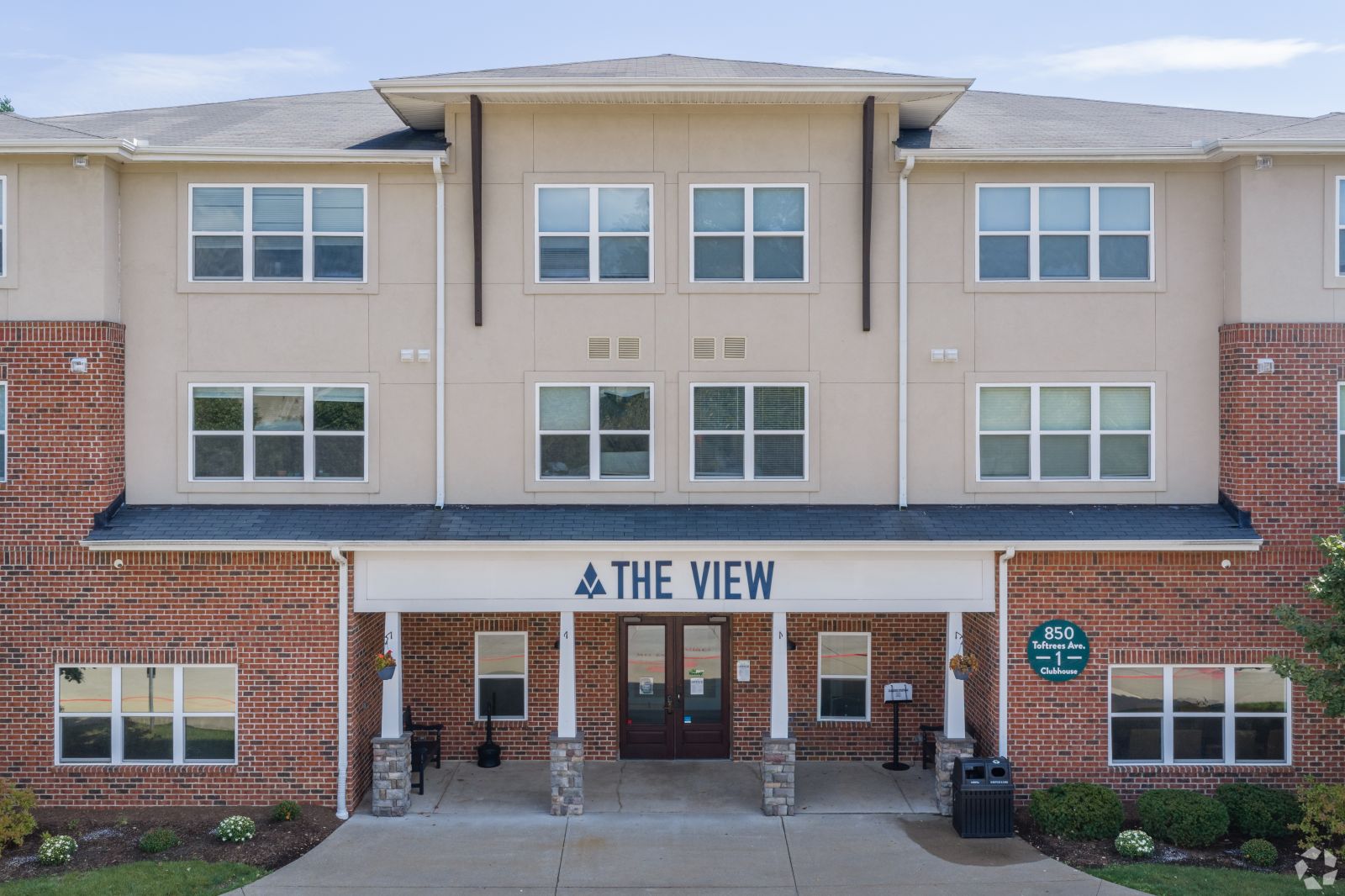 Main entrance to The View apartment building with a brick façade, covered entry, and property sign