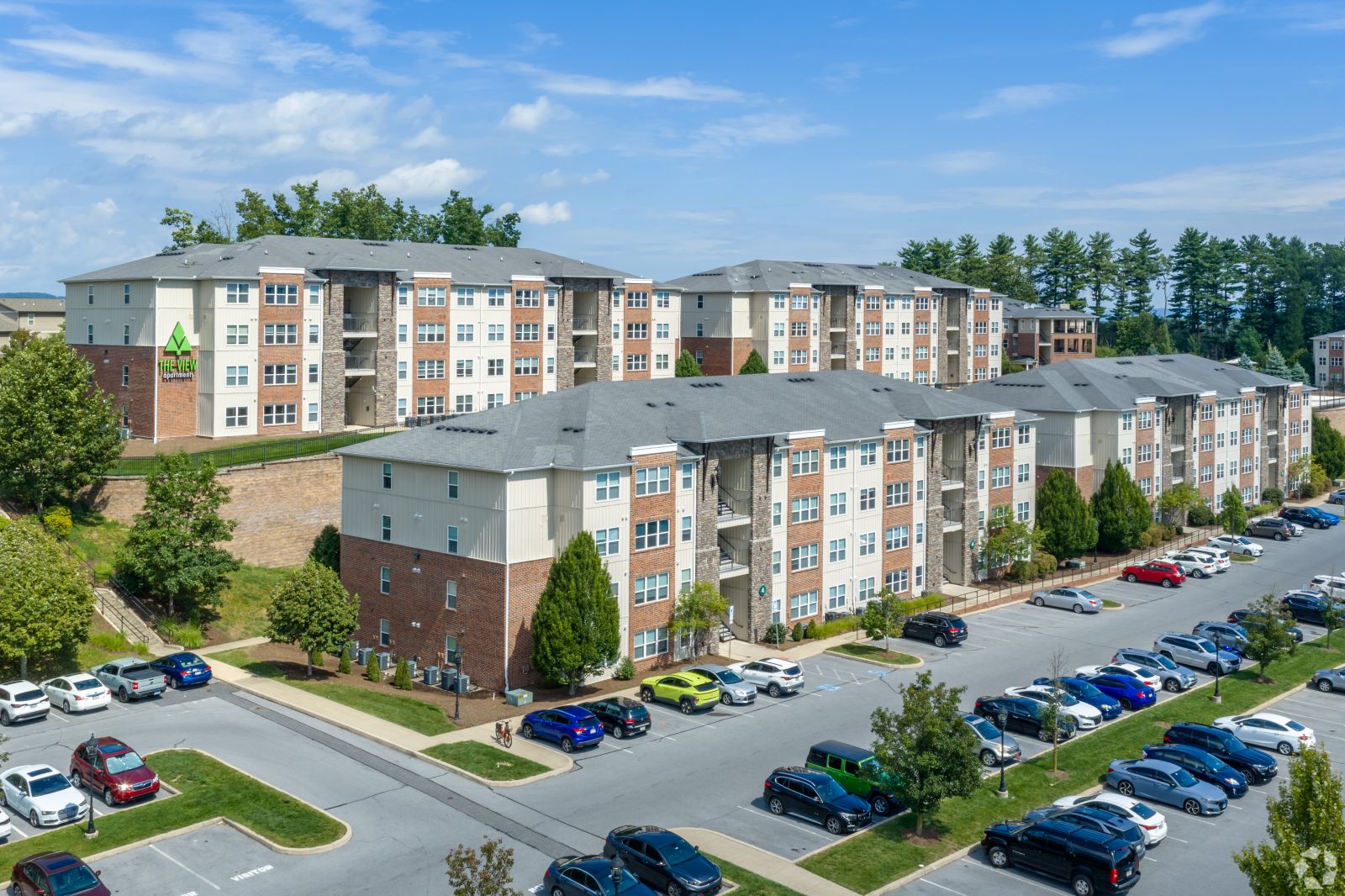 Aerial view of The View apartment buildings, parking areas, trees, and surrounding landscape