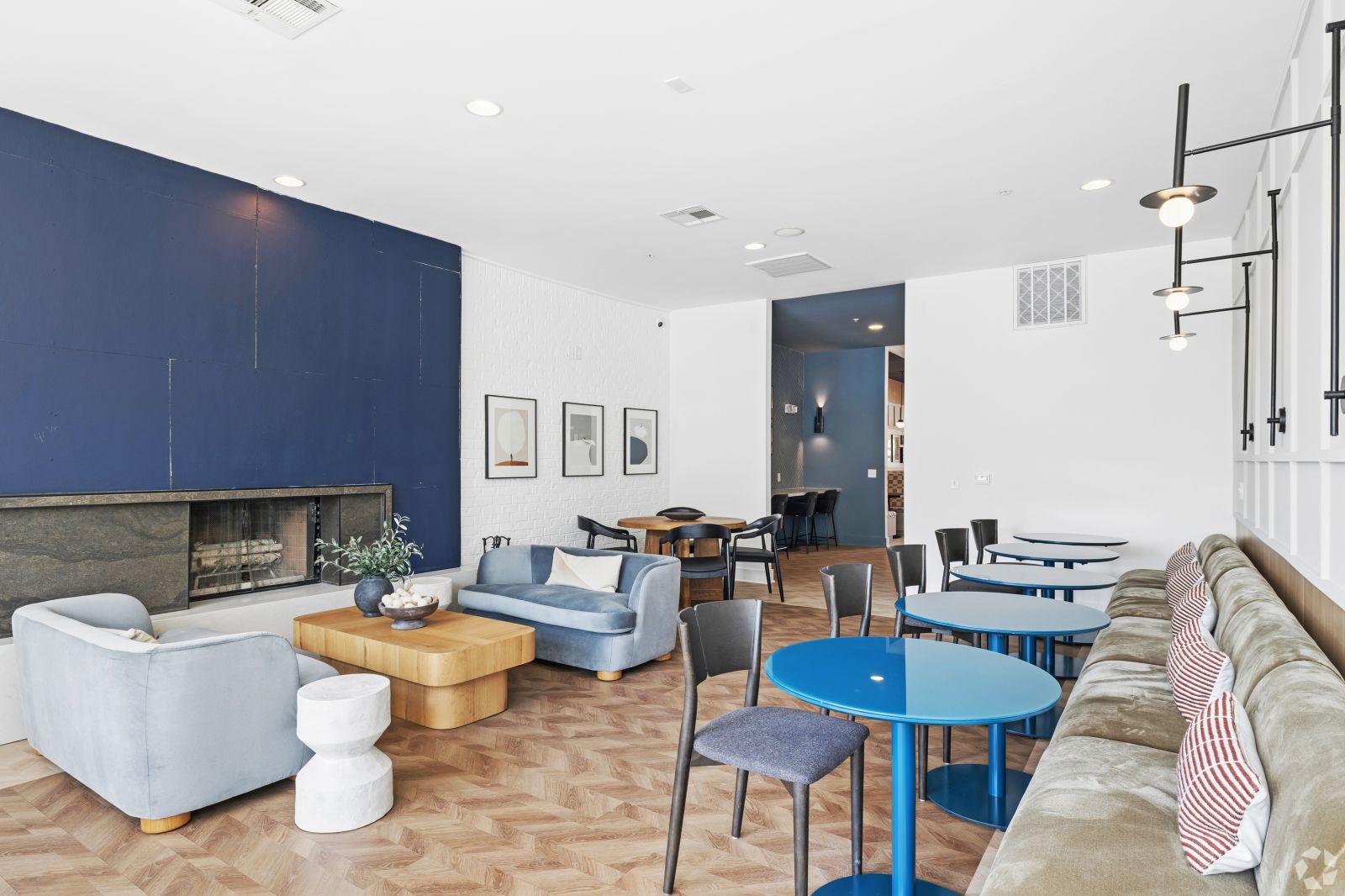 Spacious resident lounge with sofas, café tables, contemporary lighting, and a dark blue accent wall