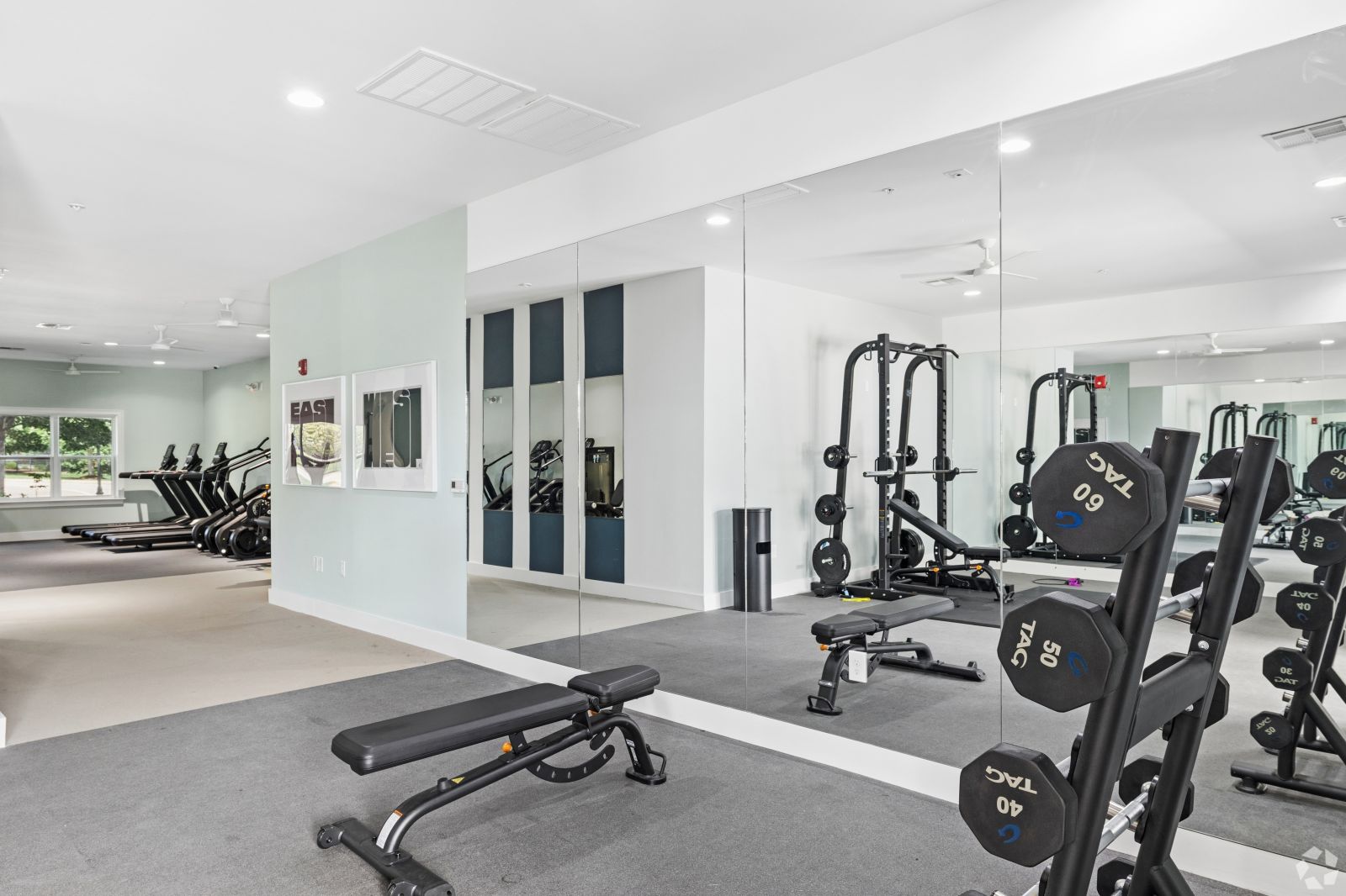 Fitness center weight area with dumbbells, benches, cable equipment, mirrors, and storage lockers