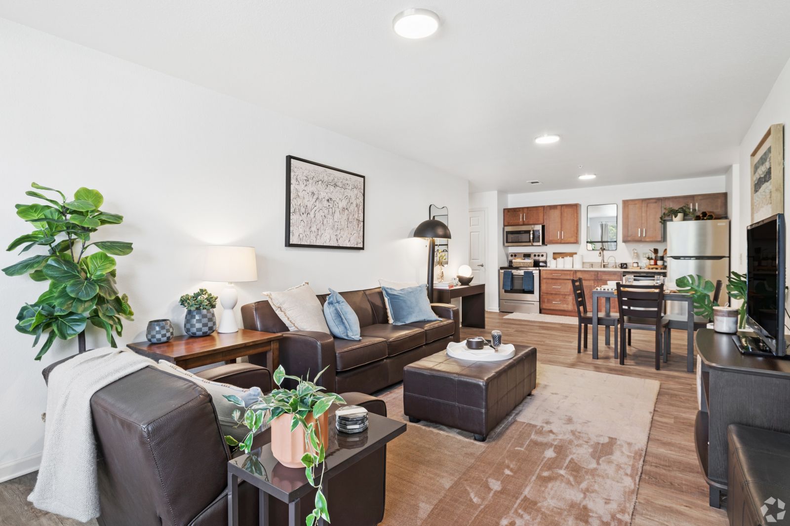 Open-plan apartment with a sectional sofa, coffee table, kitchen island, and stainless steel appliances